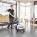 Man using a floor cleaning machine in a modern office setting