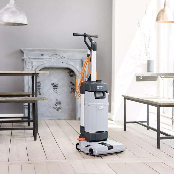 Nilfisk SC100 upright scrubber dryer cleaning wooden floors in a café setting with natural daylight.